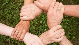 Hands joined together in a circle over grass