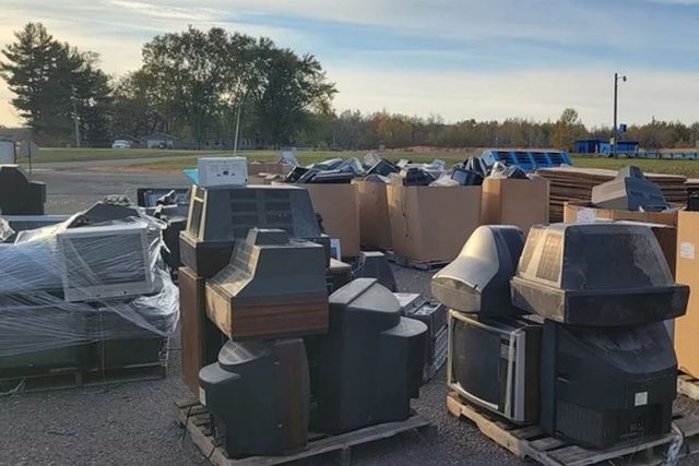 Old televisions and monitors stacked on pallets at an electronics collection event