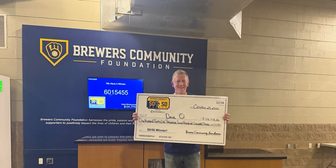 Dave Oldenberg poses with a check after winning the 50/50 raffle at American Family Field