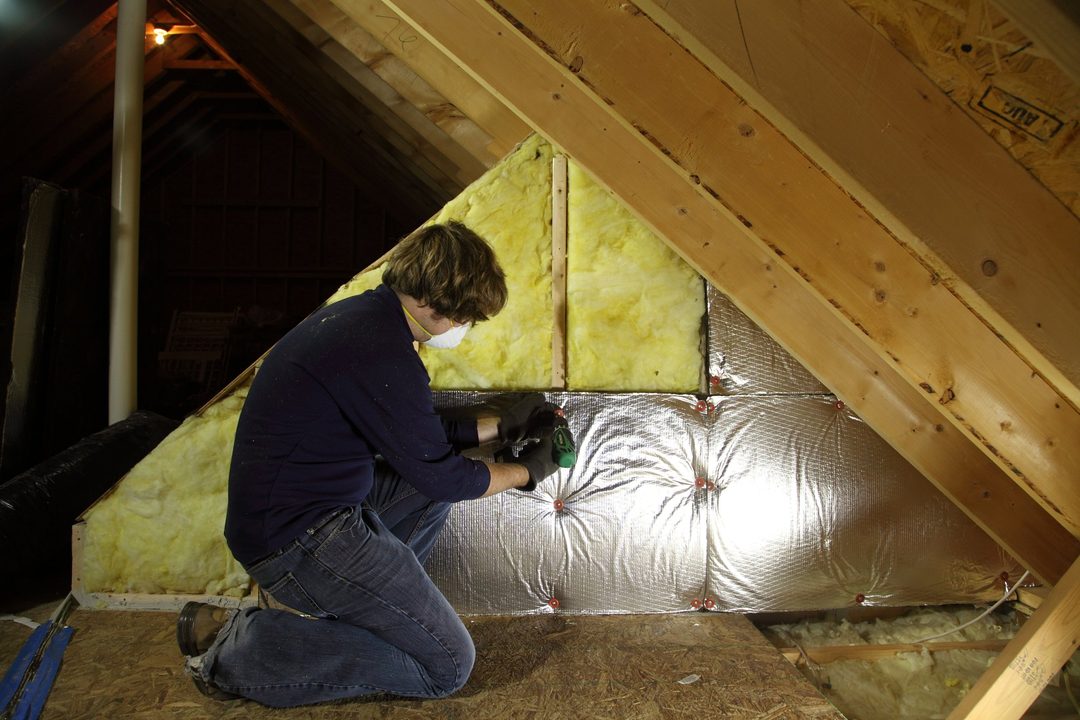 A worker installing insulation in an attic