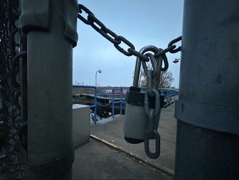 A padlock and chain securing the gate at the Menasha Lock, with the lock visible in the background