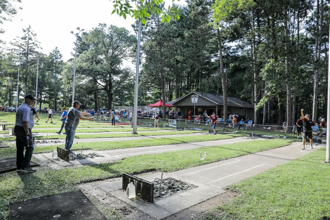 Horseshoe pitchers compete at outdoor courts during a Wisconsin horseshoe tournament