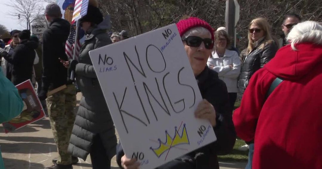 A demonstrator holds a handmade No Kings sign at an outdoor rally