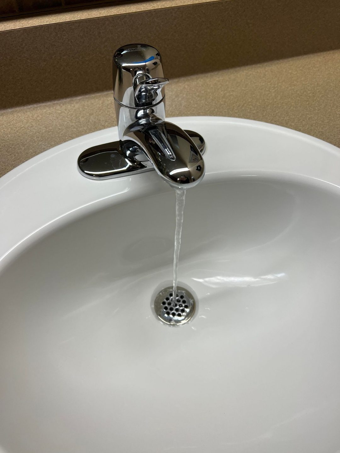A bathroom sink with water running from the faucet