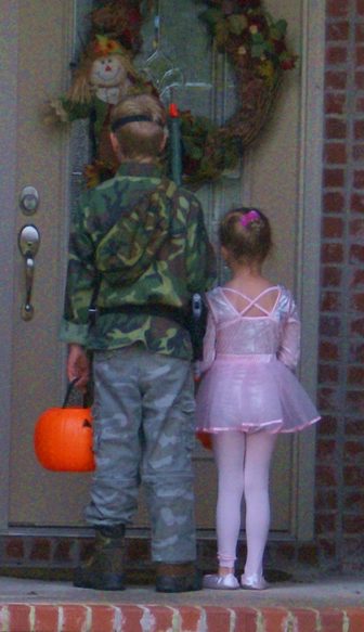 A child trick-or-treating at a house at night