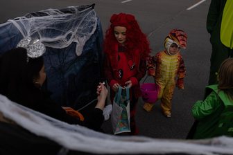 Children in Halloween costumes collect candy at a trunk-or-treat event