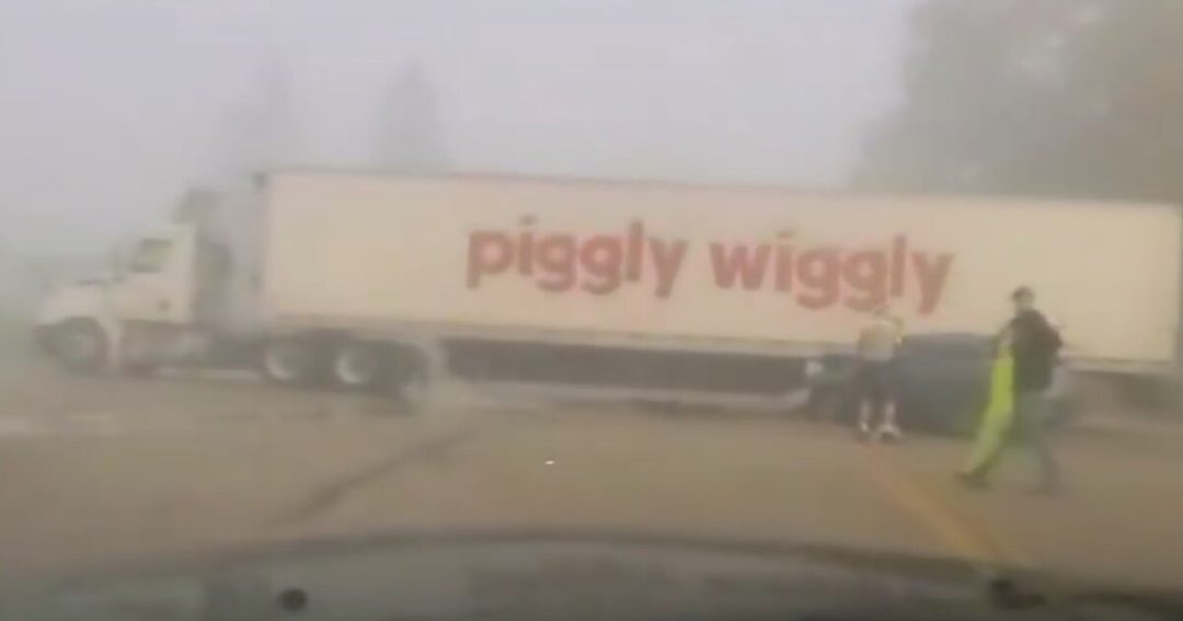 A Piggly Wiggly semi trailer in dense fog after an SUV struck its trailer at a Sheboygan County intersection