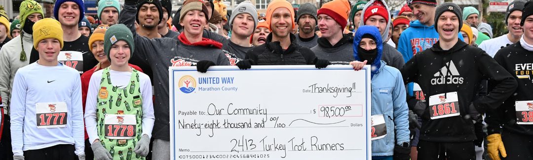Turkey Trot runners in winter hats holding a large United Way of Marathon County check