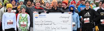 Turkey Trot runners in winter hats holding a large United Way of Marathon County check