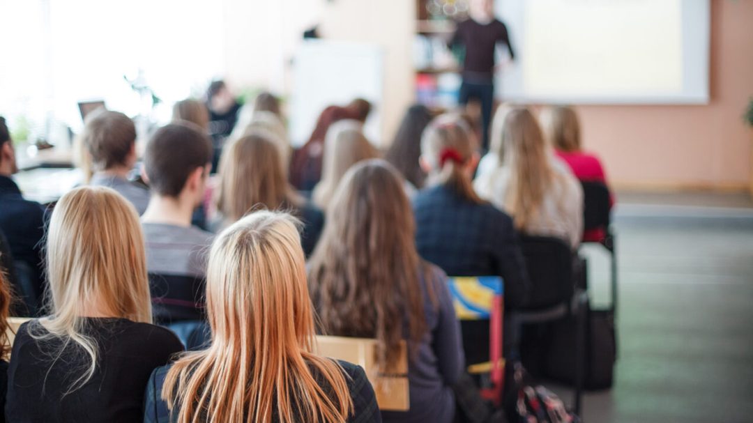 Students seated in a classroom facing an instructor and screen