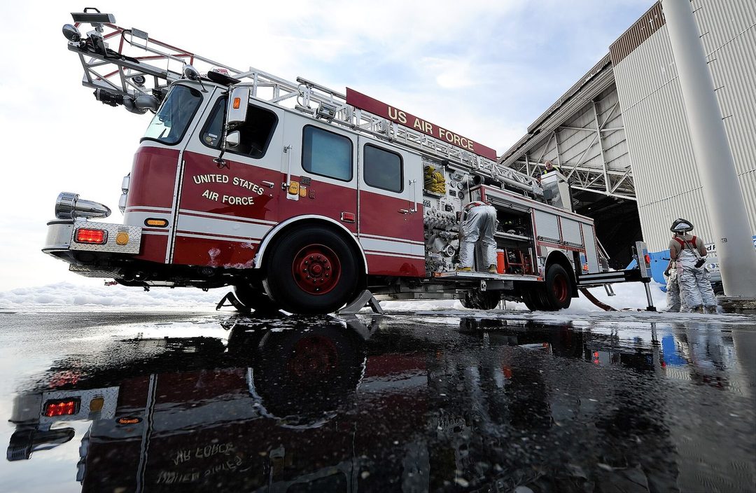 Firefighters working around fire suppression foam released inside a hangar