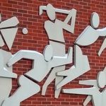 WIAA building artwork showing stylized athletes on a brick wall